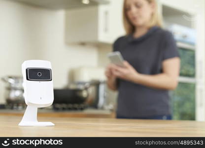 Woman Controlling Smart Security Camera Using App On Mobile Phone