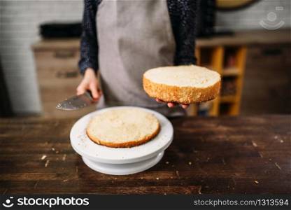 Woman cook hands holds piece of cake and knife. Homemade dessert on wooden table