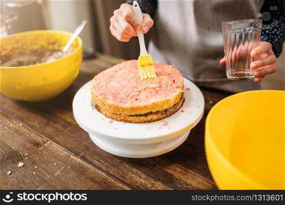 Woman cook hands smears filling for cake. Tasty dessert homemade cooking