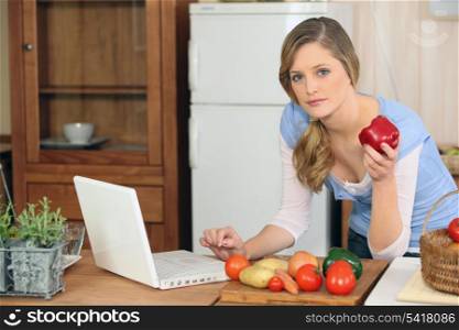 Woman cooking next to laptop