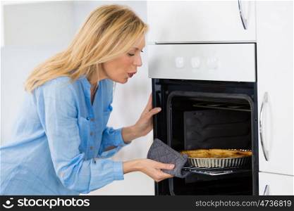 woman cooking pie in the oven at home kitchen