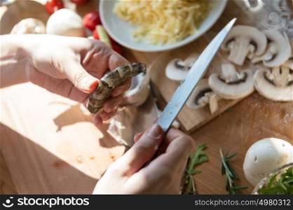 Woman cooking pizza at home. Unrecognizable woman cutting shrimp