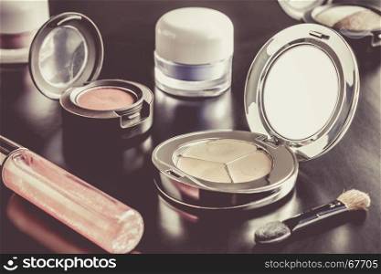 Woman cosmetics include lip gloss and eyeshadow and foundation or face powder and brush on black floor sweet style