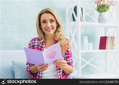 woman couch holding greeting card with mom inscription