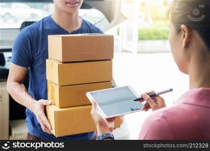 woman courier holding a parcel Shipping Mail appending signature signing delivery note after receiving package from delivery man