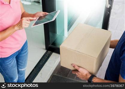 woman courier holding a parcel Shipping Mail appending signature signing delivery note after receiving package from delivery man