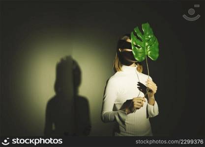 woman covering face with big green leaf