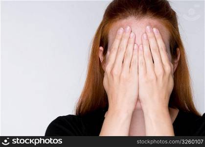 Woman covering face with hands.
