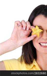 Woman covering her eye with a slice of star fruit