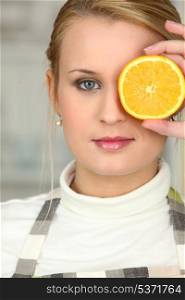 Woman covering her eye with orange slice
