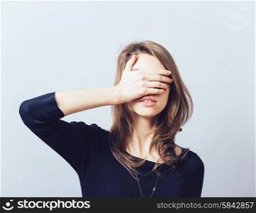 woman covering her eyes isolated on a gray background