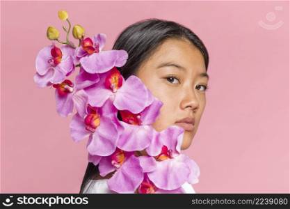 woman covering her face with orchid looking camera