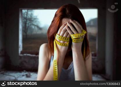 Woman covers face with her hands tied with measuring tape. Fat or calories burning concept. Weight loss. Woman covers face, hands tied with measuring tape