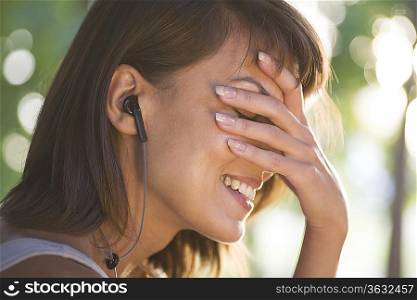 Woman covers her face laughing with headphones on