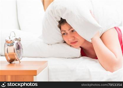 woman covers his ears a pillow to sleep