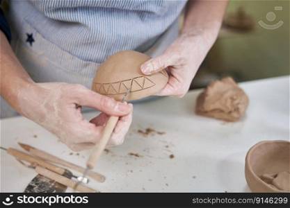 woman creates pattern on a clay pot by hands in artistic studio.. woman creates pattern on a clay pot by hands in artistic studio