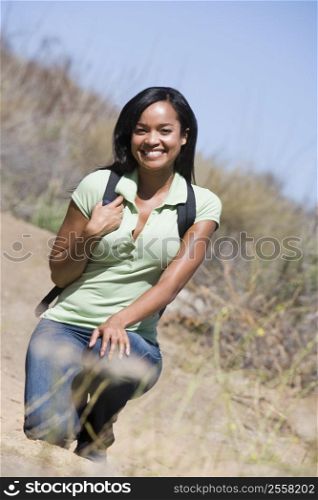 Woman crouching on beach path smiling