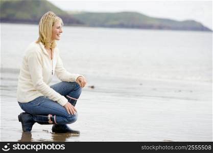 Woman crouching on beach smiling