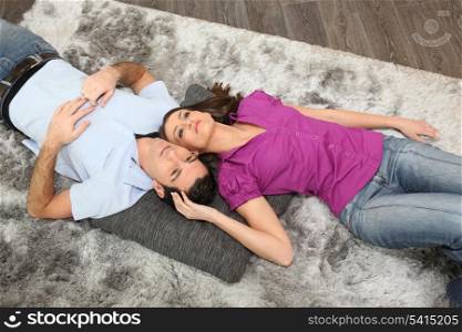 Woman cuddling man laid on a carpet