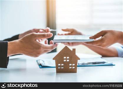 Woman customer sign agreement buying home ,salesman receive money after good deal after successful loan contract .