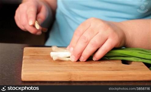 woman cuts onion for salad.