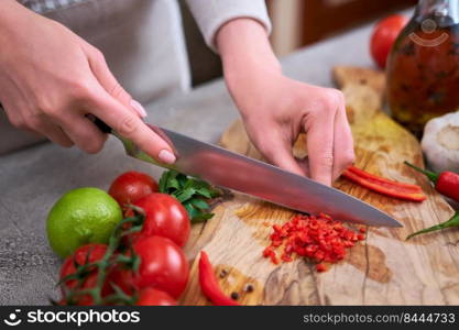 woman cutting and chili pepper by knife on wooden board.. woman cutting and chili pepper by knife on wooden board