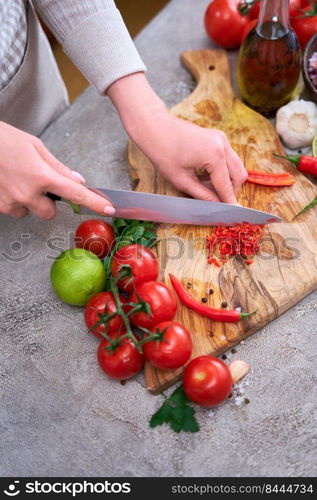 woman cutting and chili pepper by knife on wooden board.. woman cutting and chili pepper by knife on wooden board