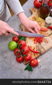 woman cutting and chili pepper by knife on wooden board.. woman cutting and chili pepper by knife on wooden board