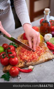 woman cutting and chopping blanched tomato by knife on wooden board.. woman cutting and chopping blanched tomato by knife on wooden board