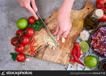 woman cutting and chopping garlic by knife on wooden board.. woman cutting and chopping garlic by knife on wooden board