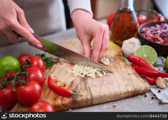 woman cutting and chopping garlic by knife on wooden board.. woman cutting and chopping garlic by knife on wooden board