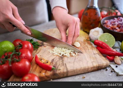 woman cutting and chopping garlic by knife on wooden board.. woman cutting and chopping garlic by knife on wooden board