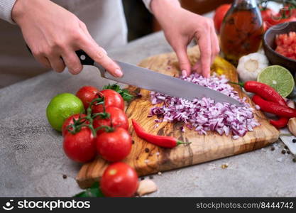 woman cutting and chopping onion by knife on wooden board.. woman cutting and chopping onion by knife on wooden board