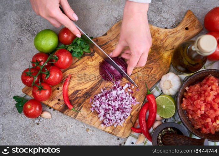 woman cutting and chopping onion by knife on wooden board.. woman cutting and chopping onion by knife on wooden board