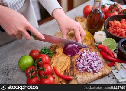 woman cutting and chopping onion by knife on wooden board.. woman cutting and chopping onion by knife on wooden board