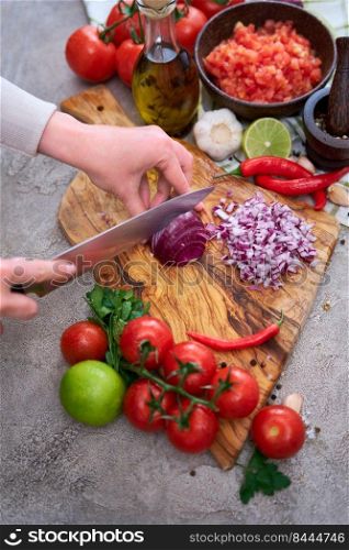 woman cutting and chopping onion by knife on wooden board.. woman cutting and chopping onion by knife on wooden board