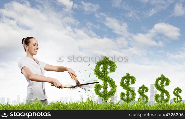 Woman cutting bush. Young happy businesswoman cutting bush shaped like dollar. Income concept