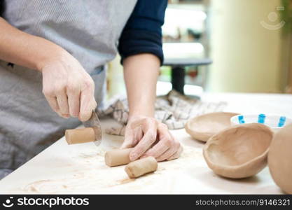 Woman cutting clay with blade standing behind table in studio.. Woman cutting clay with blade standing behind table in studio