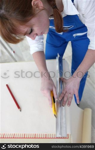 Woman cutting length of wallpaper