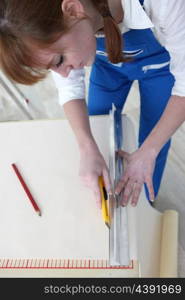 Woman cutting length of wallpaper