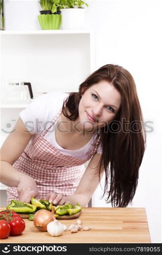 woman cutting paprika. young woman in kitchen cutting green paprika