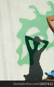 Woman dancing with shadow in front of wall