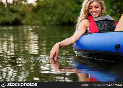 Woman dangling hand in still creek