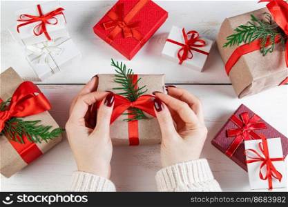 Woman decorates gift box with a red ribbon. Wrapping Christmas gifts.. Woman decorates gift box with red ribbon. Wrapping Christmas gifts.