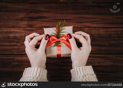 Woman decorates gift box with a red ribbon. Wrapping Christmas gifts.. Woman decorates gift box with red ribbon. Wrapping Christmas gifts.