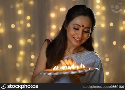 Woman decorating a plate with diyas in her hand
