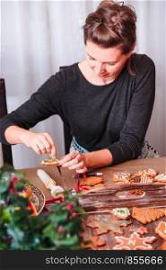 Woman decorating baked Christmas gingerbread with frosting