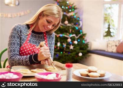 Woman Decorating Christmas Cookies In Kitchen