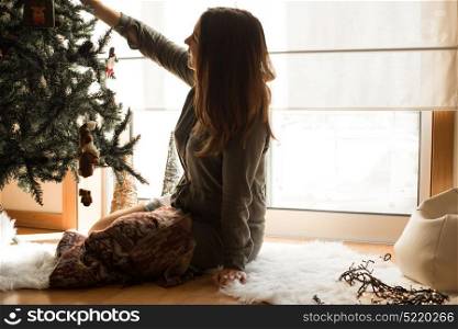 Woman decorating Christmas tree at home