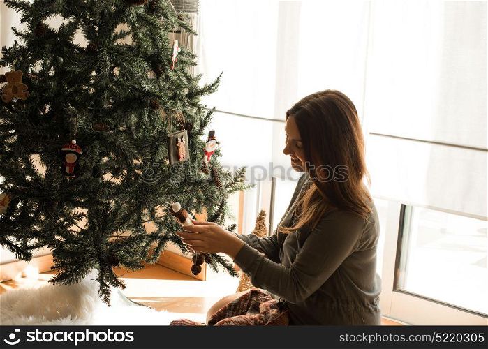 Woman decorating Christmas tree at home